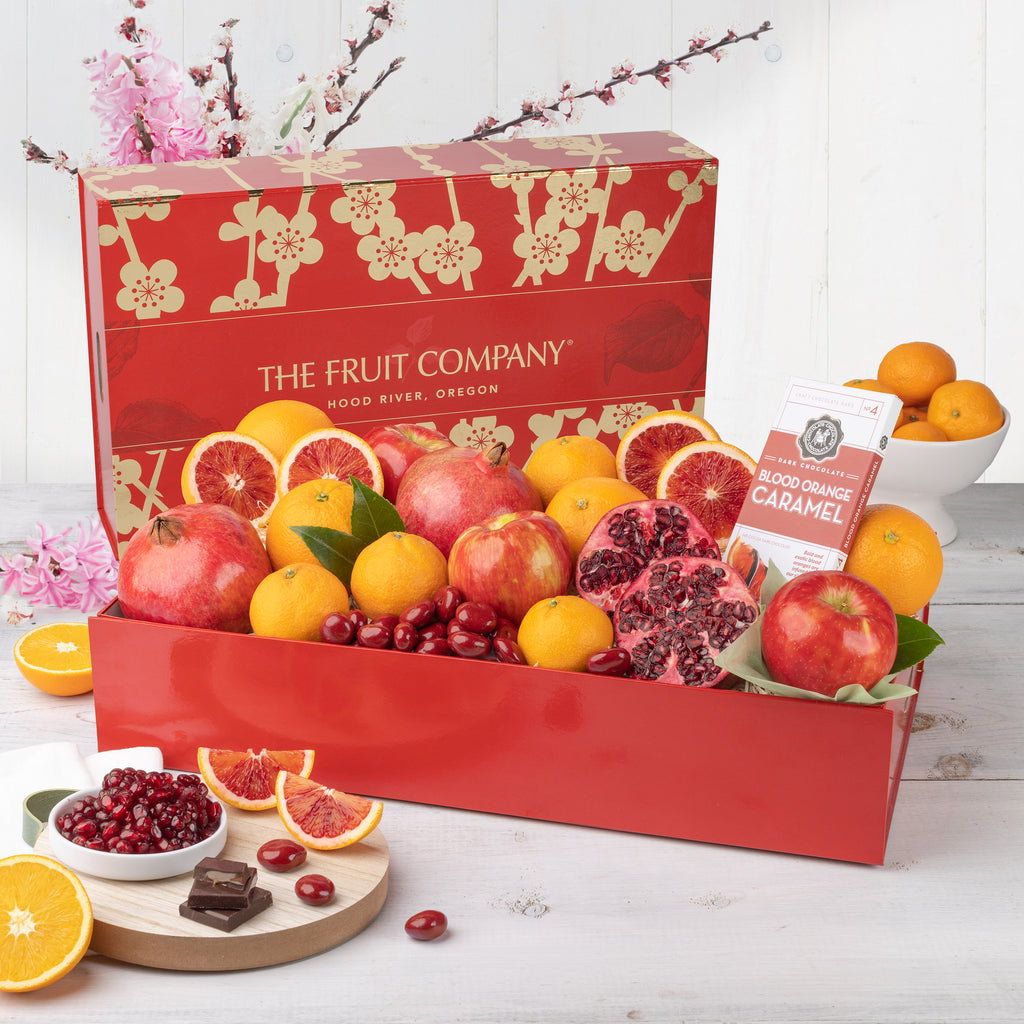 Pomegranates, blood oranges, and chocolate covered Cherries Dark chocolate blood orange caramel Oranges, apples, and pomegranates Delicious, juicy red apple Close shot of citrus, apples, and pomegranate Gorgeous red and gold Lunar New Year gift box with all of its contents
